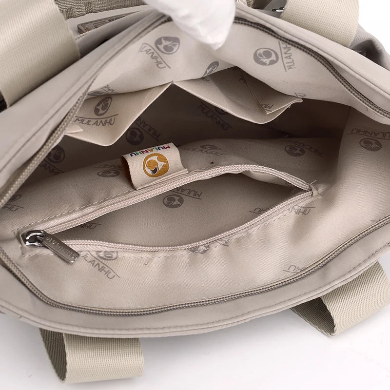 Interior view of a beige bag with zippers and a branded label.