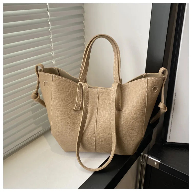 Beige tote bag with dual handles and a textured surface, displayed indoors.