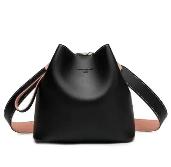 Black leather bucket bag with pink accents and adjustable strap.