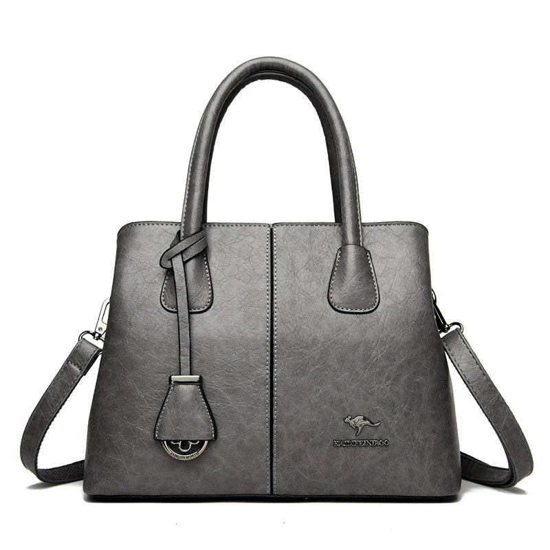 Gray leather handbag with top handles, detachable shoulder strap, and kangaroo logo on front.