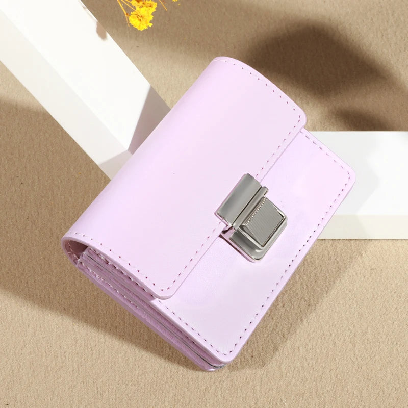 Pink wallet with silver clasp, displayed on a textured surface.