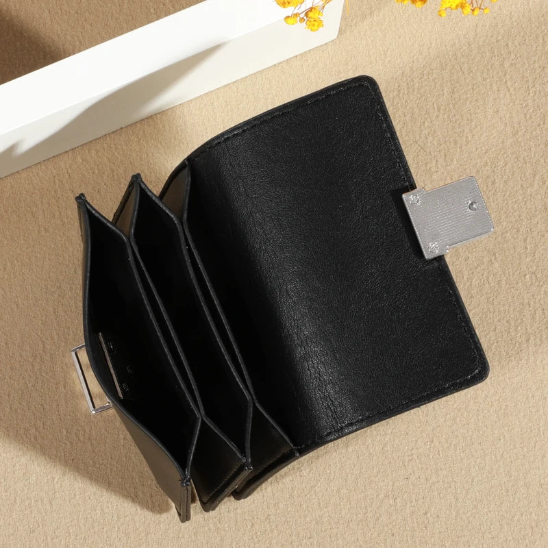Black leather wallet with multiple card slots and a metallic clasp, open for display.