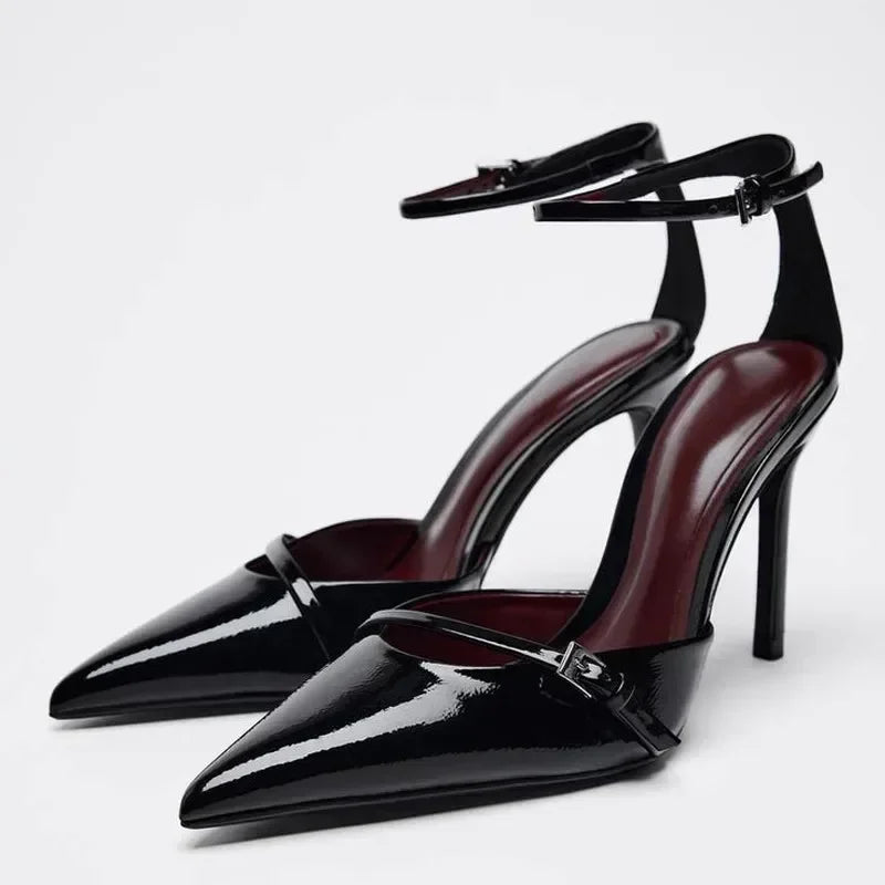 Black patent leather high-heeled shoes with ankle strap and pointed toe.