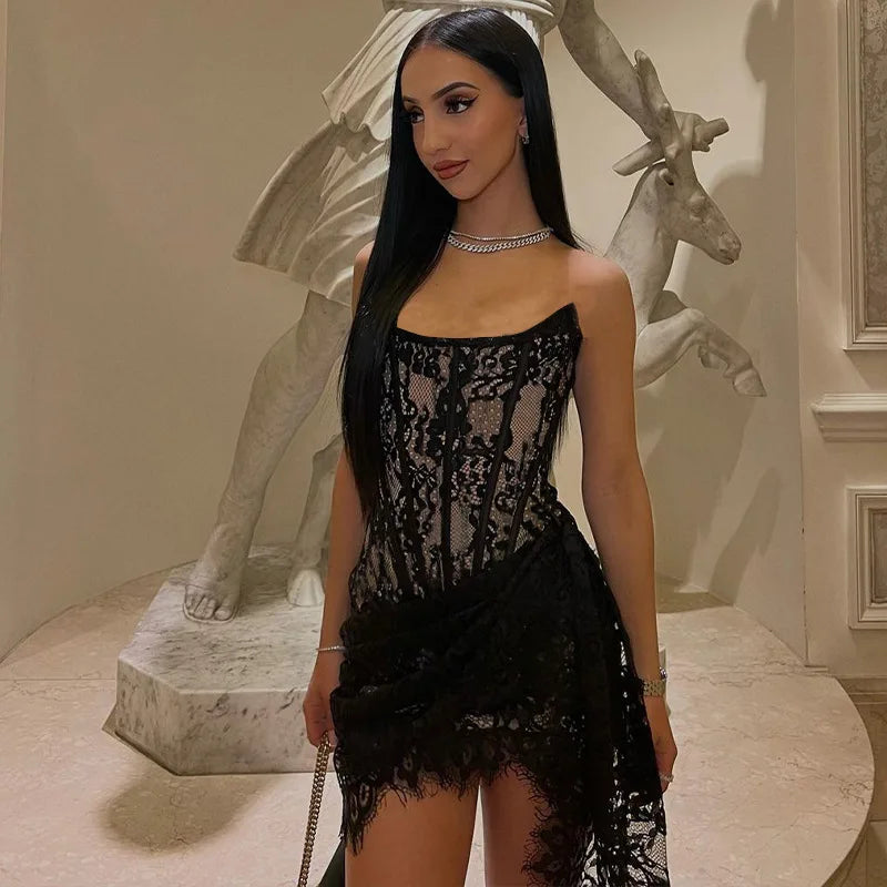 A woman wearing a black lace dress with a corset-style bodice and asymmetrical skirt.