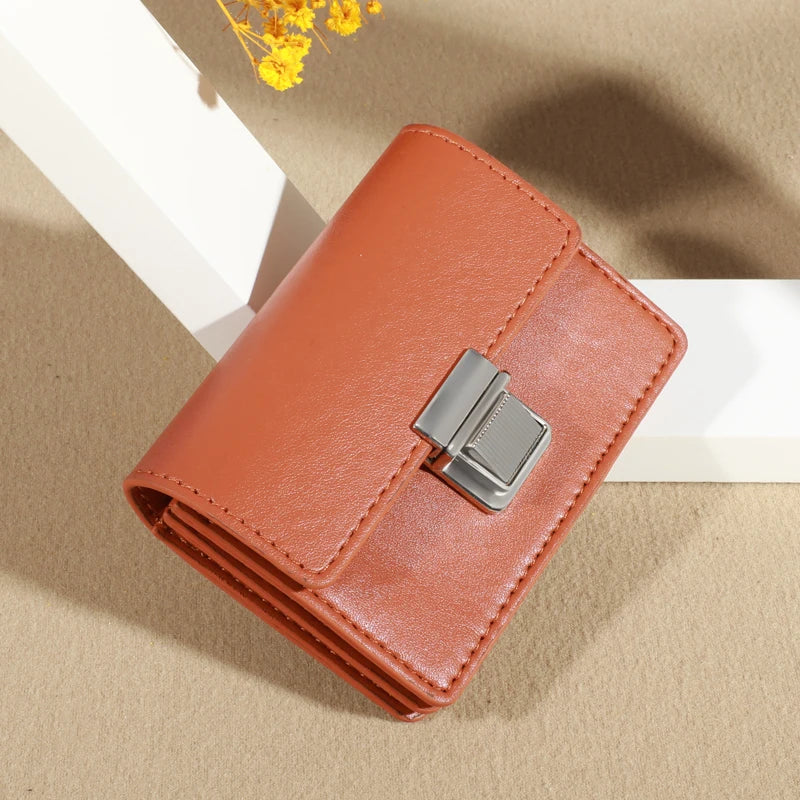 Orange leather wallet with silver clasp, displayed on a textured surface.