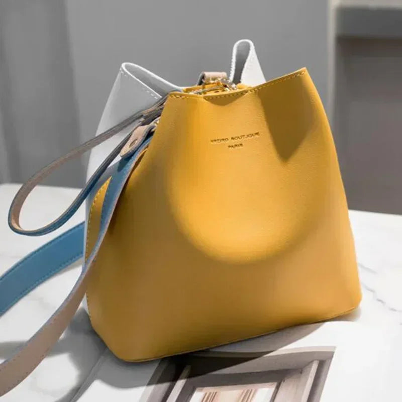 Yellow and white womens handbag with blue strap on marble surface.