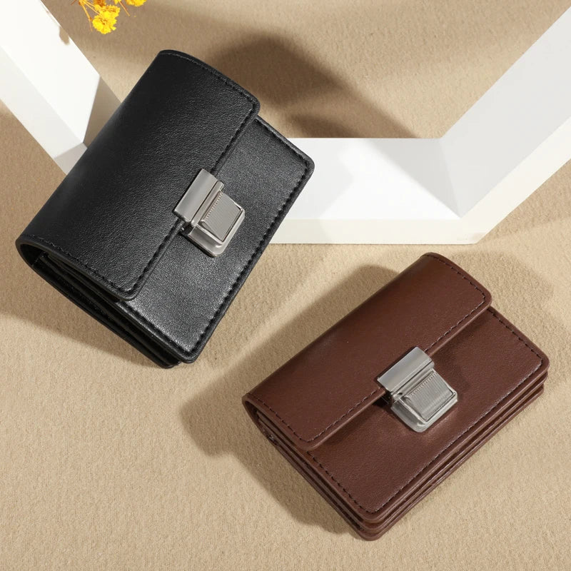 Two leather wallets, one black and one brown, with metallic clasps, displayed on a textured surface.