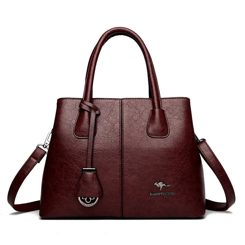 Wine-colored leather handbag with shoulder strap and brand logo on front.