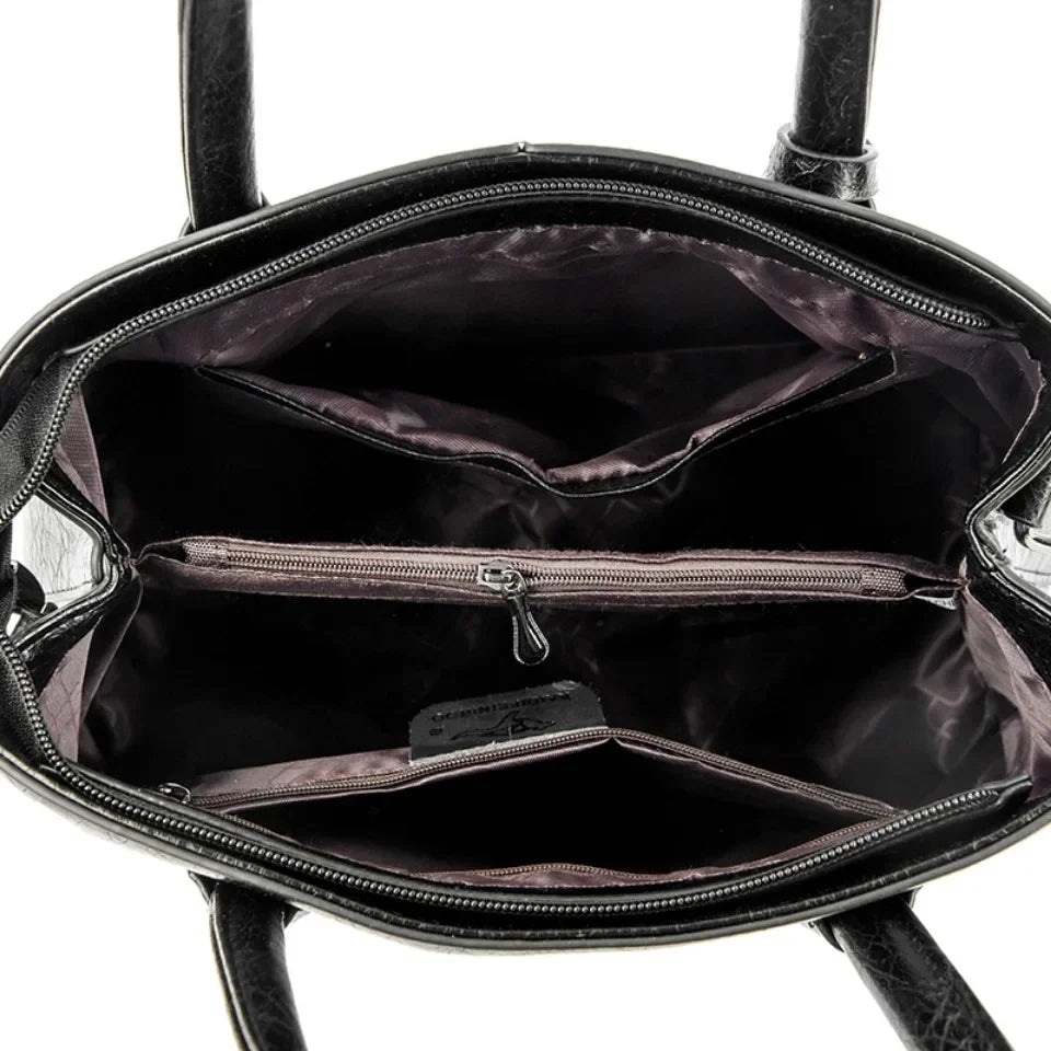 Interior view of a black leather tote bag with multiple compartments and zippers.