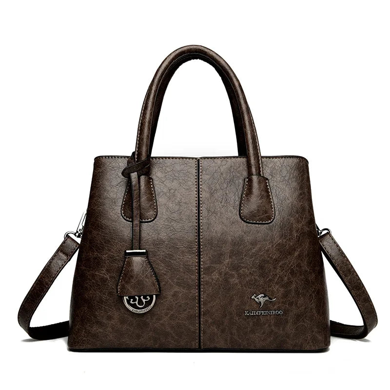 Brown leather handbag with top handle, detachable shoulder strap, and brand logo on front.