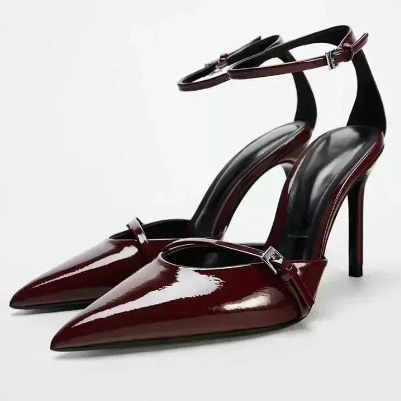 Glossy burgundy high-heeled shoes with ankle straps and pointed toes.