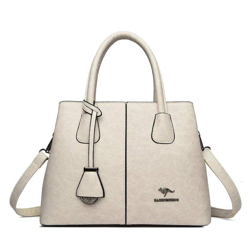 White leather handbag with kangaroo logo and adjustable strap on a plain background.